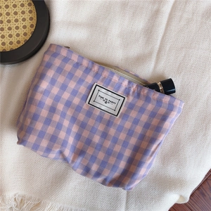 Close-up of a plaid cotton makeup bag with a zipper and Time to Party woven label