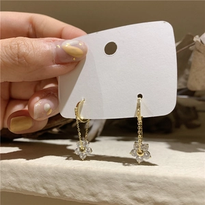 Detail showing gold floral drop earrings with sparkling rhinestones and elegant petals