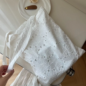 Close-up of white cotton tote bag featuring delicate hollow floral embroidery detail