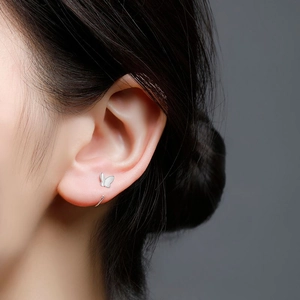 Close-up of a silver butterfly earring on a model's ear for a minimalist jewelry look