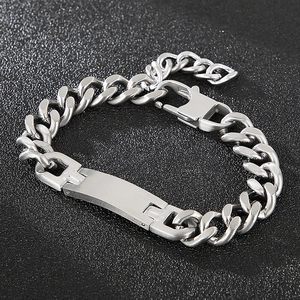 Gros plan d'un bracelet gourmette argenté avec plaque en métal brossé et fermoir mousqueton