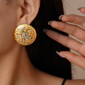 Close-up of golden starfish earrings with colorful abalone shell inlay worn by model