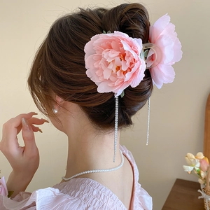 Detail of pink fabric flower hair claw clip with dangling rhinestone tassels in hair