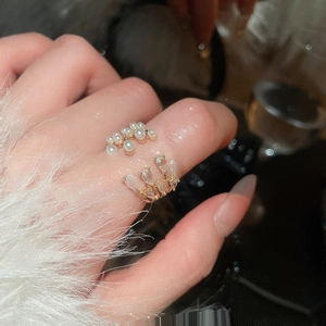 Detailed view of gold crown ring with white pearls and zircons worn on model finger