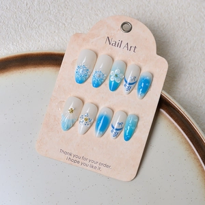 Detail of 3D floral and bow press-on nails with blue-white gradient and pearls