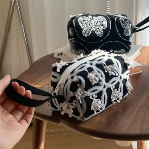 Close-up of black canvas hand bags with elegant white floral and butterfly embroidery
