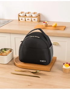 Detail of black semi-circular lunch bag with mesh side pocket and sturdy handle