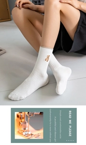 Detail of white cotton crew socks featuring cute brown bear embroidery and ribbed texture
