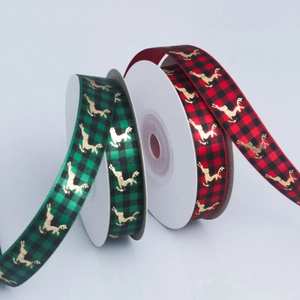 Close-up of red and green plaid Christmas ribbons with golden reindeer print details