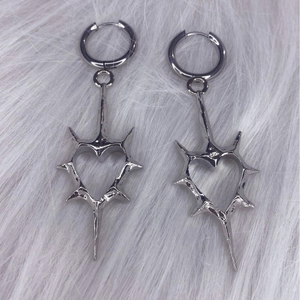 Silver thorn heart hoop earrings with hollow Y2K design on soft white faux fur background