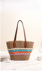 Close-up of woven straw tote bag with rainbow stripes and brown leather handles