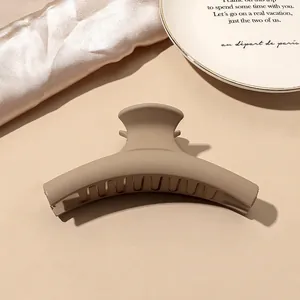 Close-up of matte milk tea large hair claw clip on elegant satin and ceramic plate