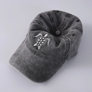 Detailed view of turtle embroidery on dark grey washed cotton baseball cap texture