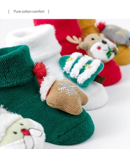 Detailed close-up of pure cotton baby Christmas socks with cute plush 3D ornaments