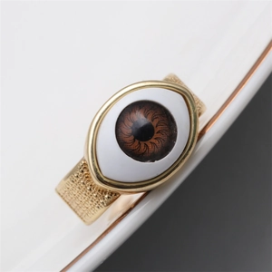 Macro shot of gold-plated open ring featuring a unique eye-shaped resin design and texture