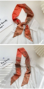 Detail of artistic abstract orange and grey skinny silk scarf tied in a knot and hanging
