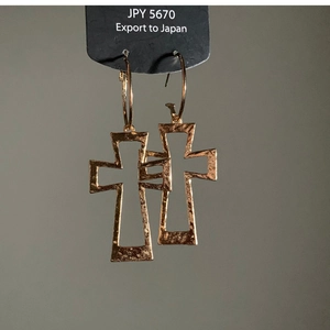 Detail of gold hammered cross earrings showing vintage textured finish and round hoop