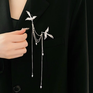 Close-up of silver swallow brooch with pearl tassels on black blazer lapel