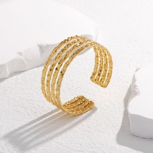 Détail de la texture martelée dorée sur un bracelet jonc multicouche ouvert en acier
