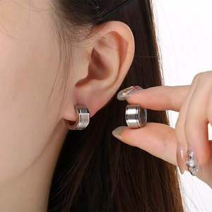 Detail of silver C-shaped huggie earring with brushed metal finish and polished edges