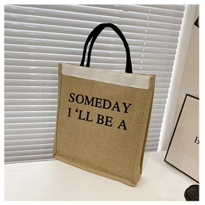 Close-up of a minimalist linen tote bag with black handles and bold typography