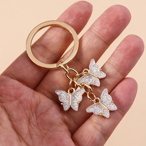 Detail of three white butterfly charms with silver sequins and golden keyring loop