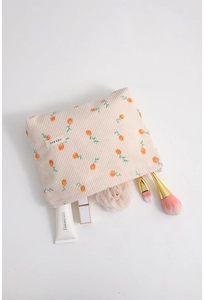 Flat lay of floral corduroy makeup bag with citrus print and daily beauty essentials