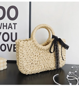 Detail of woven straw handbag with black lace bow and round handles for beach vacation