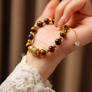 Detailed shot of tiger eye beads bracelet with golden charm and zircon pendant on wrist