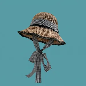 Detail of hand-woven straw hat featuring a gingham bow ribbon and black brim edging