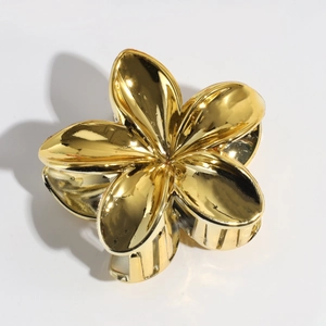 Detail of golden five-petal flower hair claw clip with glossy electroplated metal finish
