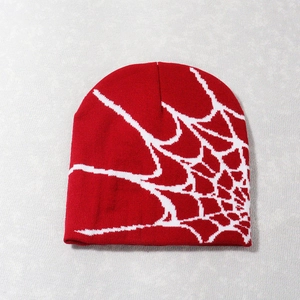 Detailed close-up of red knit beanie with white spider web jacquard pattern embroidery