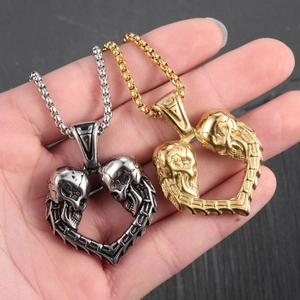 Colliers avec pendentif cœur double crâne vintage en argent et or tenus dans la main