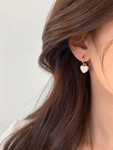 Détail de boucle d'oreille cœur avec anneau doré sur modèle montrant la texture raffinée