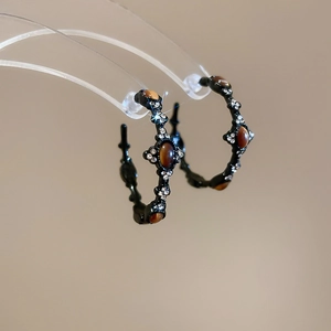 Close-up of vintage C-shape earrings with tiger eye stones and diamonds on a rack