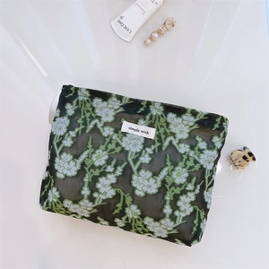 Detail view of floral embroidered mesh makeup bag with simple wish label and zipper