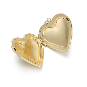 Detailed macro of a polished gold heart locket in open state showing the photo compartment