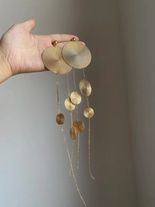 Macro detail of gold tassel earrings featuring spiral textures and layered metallic rings