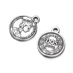 Close-up of vintage silver alloy coin pendants featuring Elizabeth II and Dos Pesos relief