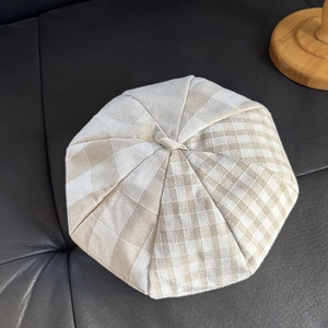 Detailed view of the plaid pattern and stitched texture on a linen newsboy cap
