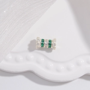 Détail macro d'une perle en argent sertie de zircons vert émeraude et blancs brillants