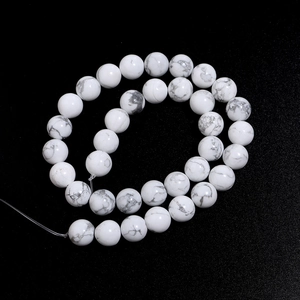 Macro shot of white turquoise beads with grey veins on a black textured background