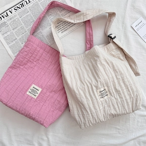 Flatlay view of pleated canvas tote bags in pink and beige with adjustable straps