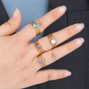 Detail view of stacked gold-plated stainless steel rings with colorful zircon stones on hand