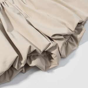 Detail shot of beige ruched fabric showing smooth texture and high-quality stitching