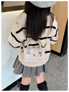 Detailed view of pink tweed mini purse with pearl handle and rhinestone bow accessories
