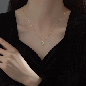 Elegant gold starburst pendant necklace with light blue gemstone worn by a model