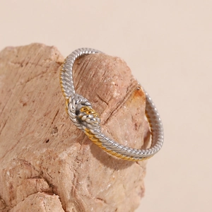 Macro shot of two-tone twisted knot ring in gold and silver on natural rock