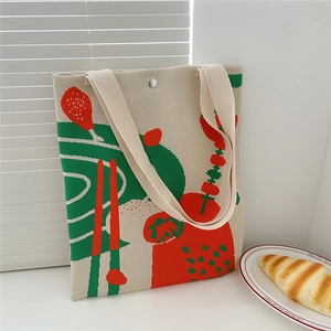 Detail of knitted floral tote bag showing woven texture and magnetic buckle closure