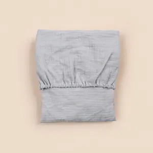 Close-up of light gray cotton gauze cradle fitted sheet with elastic edges and texture